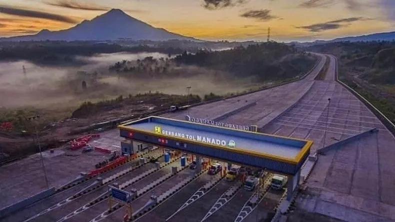 Gerbang tol saat matahari terbit dengan latar gunung berkabut